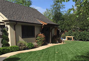 Angled view of a two-story home’s side entrance, with a curving path and subtle architectural features