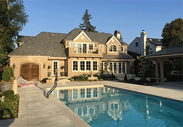 Late-afternoon backyard view of a stately two-story home and swimming pool