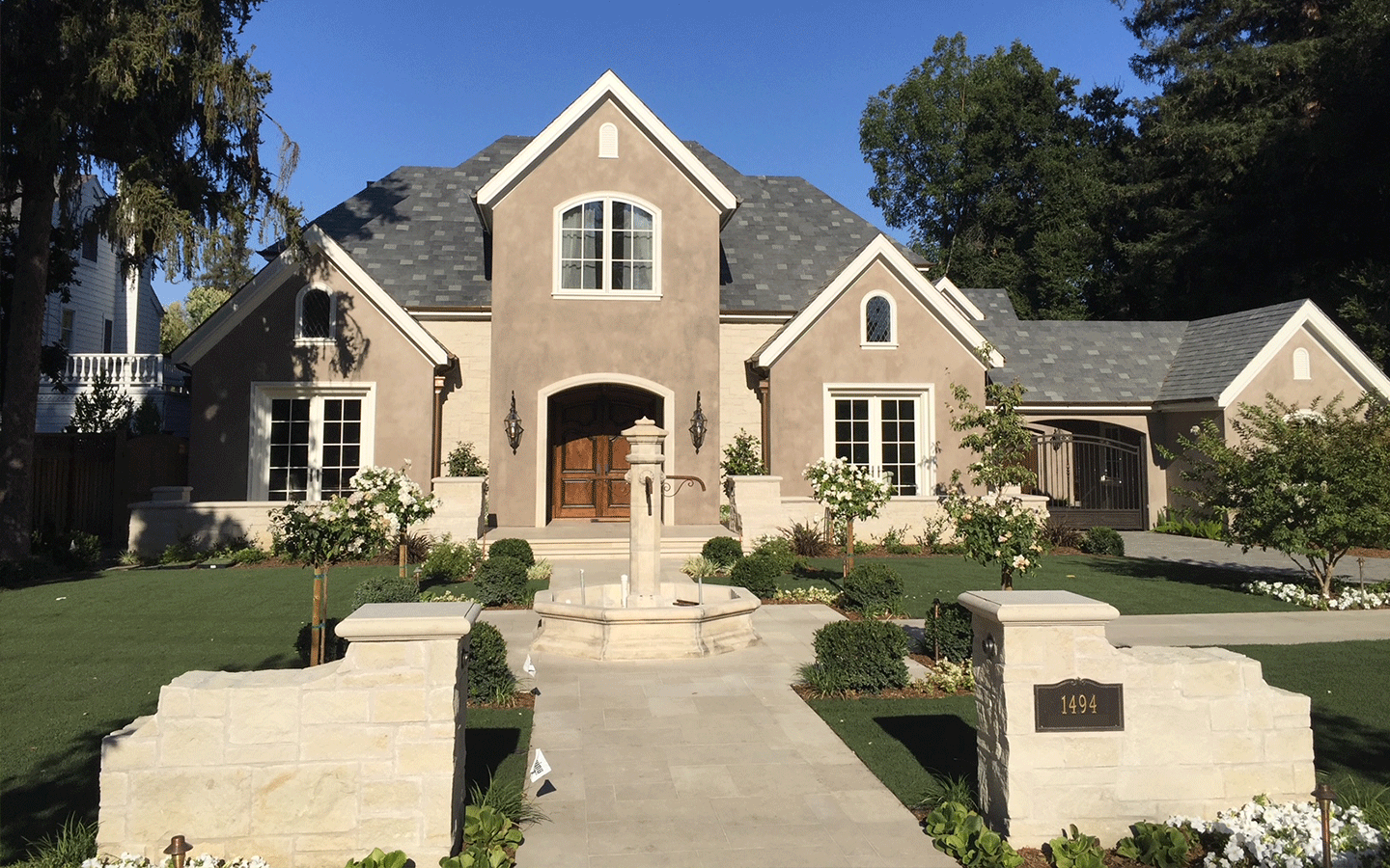 Front view of a large, stately, two-story brick-and-stonework home with multiple gables